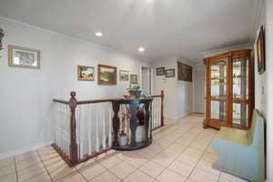 Hallway featuring light tile patterned floors, baseboards, recessed lighting, crown molding