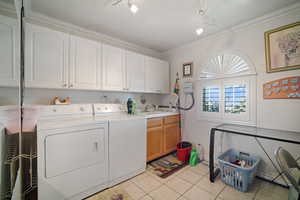 Washroom with washer and dryer, cabinet space, rail lighting, light tile patterned flooring, and ornamental molding