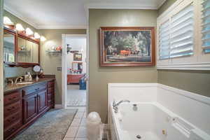 Main floor primary bathroom with a tub with jets, vanity, tile patterned floors, and crown molding