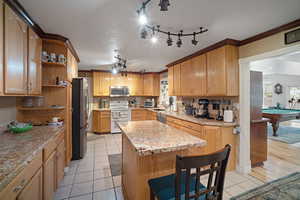 Kitchen open shelves, light tile patterned floors, a kitchen island, and crown molding