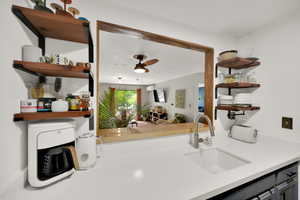 Kitchen with a sink, open shelves, ceiling fan, and light countertops