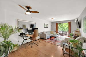 Living area with wood finished floors, a desk, and a ceiling fan