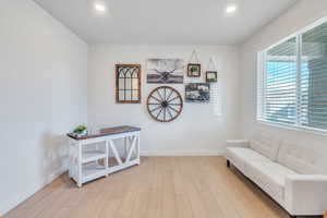 Sitting room with light wood-style floors, baseboards, and recessed lighting