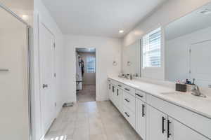 Full bathroom featuring healthy amount of natural light, double vanity, an enclosed shower, baseboards, and recessed lighting