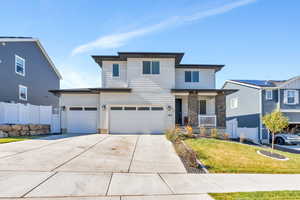 View of front of house featuring driveway, a porch, a garage, and stone siding