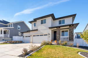 View of front of property featuring a porch, a garage, driveway, and stone siding