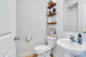 Bathroom with a sink, baseboards, toilet, and wood finished floors
