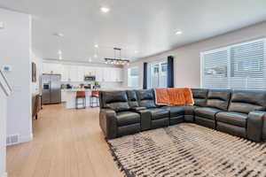 Living room with light wood-style flooring, recessed lighting, a textured ceiling, and baseboards