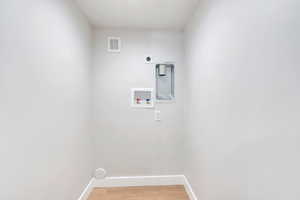 Clothes washing area featuring washer hookup, baseboards, electric dryer hookup, and light wood-style floors