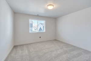 Empty room with carpet floors, a textured ceiling, and baseboards