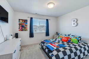 Bedroom with light carpet, baseboards, and a textured ceiling