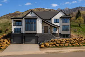 View of front of property featuring a mountain view, stucco siding, a garage, and driveway