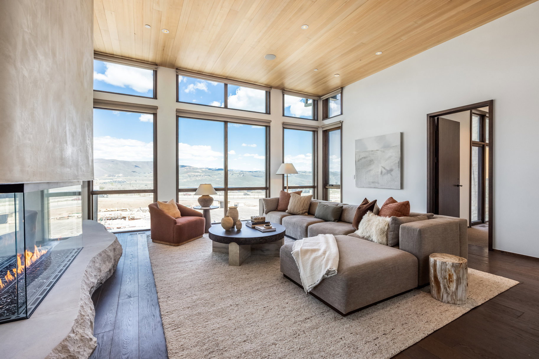 Living area featuring wood ceiling, dark wood finished floors, a mountain view, a multi sided fireplace, and a high ceiling