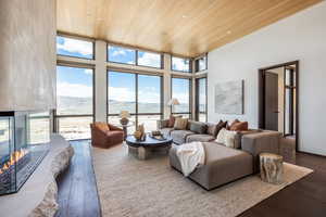 Living area featuring wood ceiling, dark wood finished floors, a mountain view, a multi sided fireplace, and a high ceiling