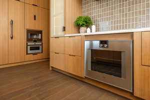 Kitchen featuring oven, beverage cooler, dark wood-style flooring, and light countertops
