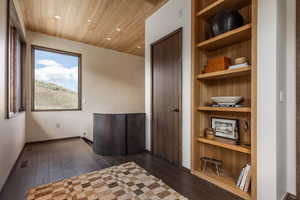 Unfurnished room with recessed lighting, dark wood-style floors, wooden ceiling, built in shelves, and baseboards