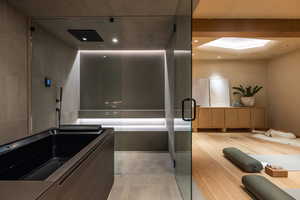 Full bathroom with elevator, a skylight, and a shower with shower door