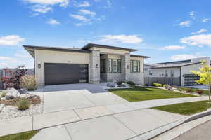 Contemporary house featuring a garage, driveway, and stucco siding