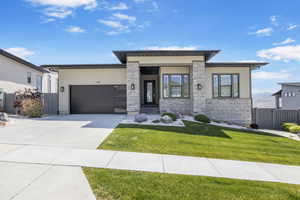 View of front of home featuring a garage, driveway, and stone siding