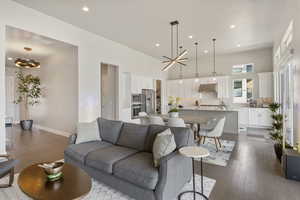 Living area featuring a chandelier, dark wood-type flooring, recessed lighting, baseboards, and a towering ceiling