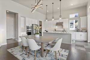 Dining room featuring a towering ceiling, baseboards, dark wood finished floors, recessed lighting, and a chandelier