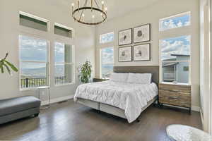 Master suite with a chandelier, multiple windows, dark wood finished floors, high ceiling and beautiful views.