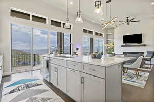 Kitchen featuring a sink, an island with sink, hanging light fixtures, recessed lighting, and elegant quart countertops