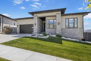 View of front of property featuring stone siding, concrete driveway, and a garage