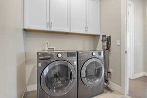 Washroom with cabinet space, washer and clothes dryer, and baseboards