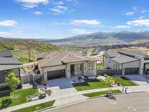 View of front of house with concrete driveway, a mountain view, an attached garage, roof with shingles, and a residential view