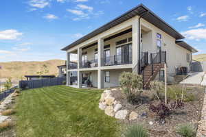 Back of property featuring stucco siding, central AC, a balcony, and a mountain view