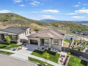 View of front of home with an attached garage, concrete driveway, stone siding, and a mountain view