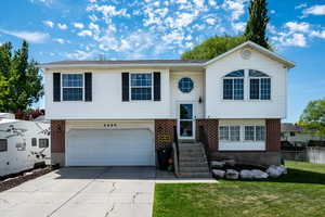 Split foyer home with brick siding, driveway, an attached garage, and entry steps