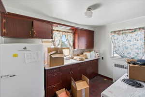 Kitchen with freestanding refrigerator, radiator heating unit, light countertops