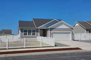View of front of house featuring an attached garage, a fenced front yard, concrete driveway, and a gate