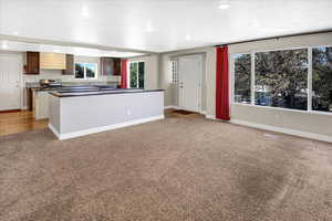 Kitchen featuring light carpet, dark countertops, plenty of natural light, baseboards, and recessed lighting