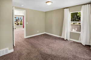 Empty room featuring carpet flooring, baseboards, and a smoke detector