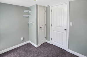 Unfurnished bedroom with baseboards and dark colored carpet