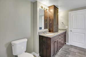 Full bath featuring toilet, double vanity, and baseboards