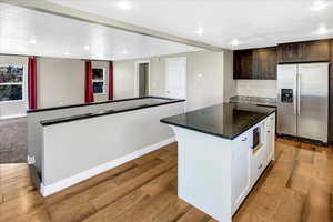 Kitchen with appliances with stainless steel finishes, a center island, baseboards, light wood-style floors, and recessed lighting