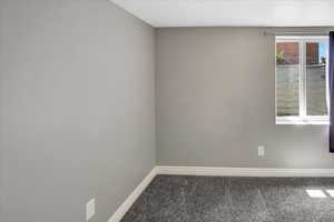Carpeted spare room featuring baseboards