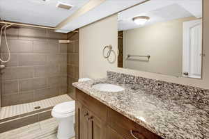 Bathroom with tiled shower, toilet, and vanity