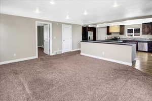 Kitchen with stainless steel appliances, carpet floors, recessed lighting, baseboards, and dark brown cabinets