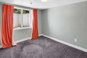 Carpeted spare room featuring baseboards and a textured ceiling