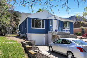 Single story home with an attached garage, a mountain view, concrete driveway, a porch, and stucco siding