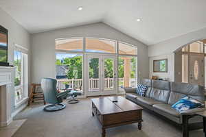 Living area with arched walkways, lofted ceiling, carpet flooring, a textured ceiling, and recessed lighting