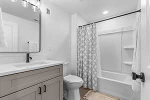 Full bath featuring toilet, vanity, shower / tub combo, and wood finished floors