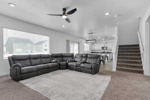 Living room with light colored carpet, ceiling fan, stairway, recessed lighting, and baseboards