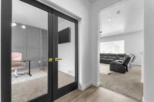 Doorway to outside featuring wood finished floors, baseboards, and carpet