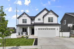 Modern farmhouse with covered porch, board and batten siding, an attached garage, and concrete driveway